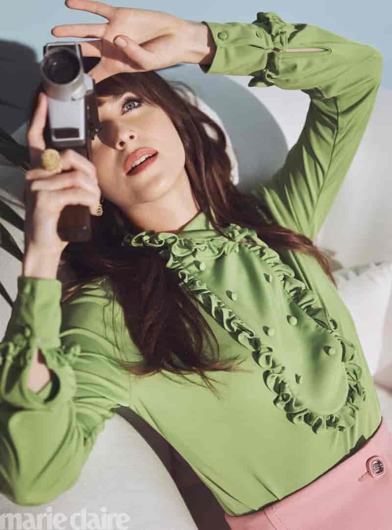 Posing with a camera, Dakota Johnson wears a Prada top and shirt with Cartier jewelry.