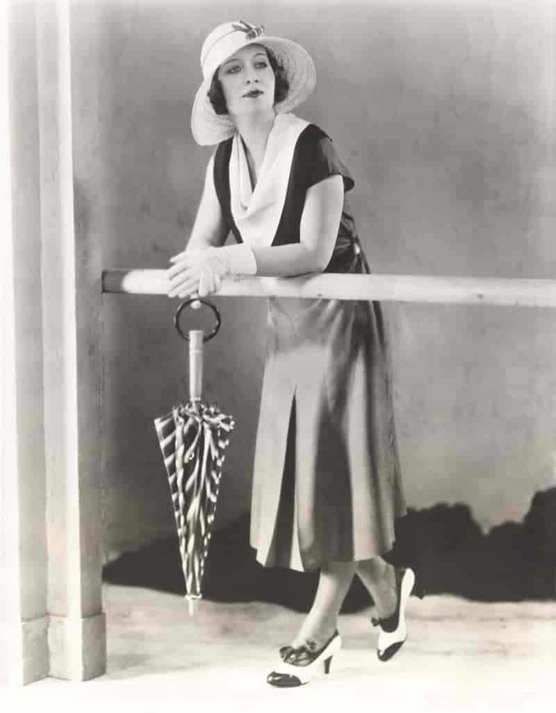 Woman poses in a daytime look including cowl neck dress, sun hat, and short gloves. Photo: Shutterstock.com